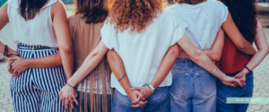 group of women freinds holding hands facing the sunset