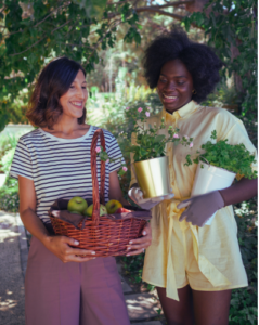 2 women holding plants talking to each other