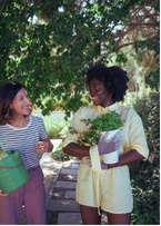 2 women holding plants talking to each other